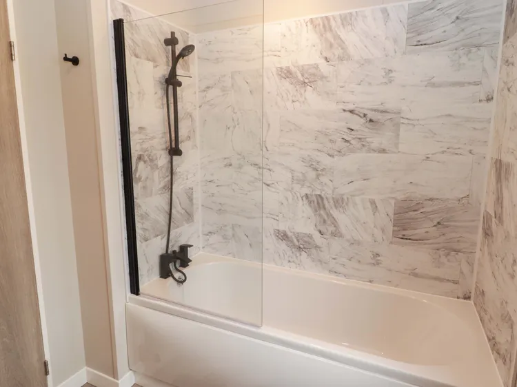 Family bathroom with bath, shower over and heated towel rail at Awel y Môr (Dolphin)