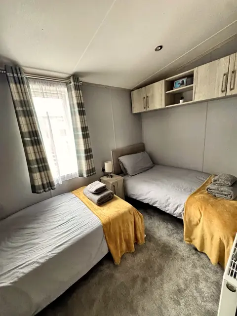 Twin room at Tŷ'r Môr with overhead storage and bright window