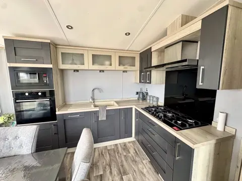 Kitchen at Tŷ'r Môr with gas hob, built-in oven, microwave and dark contemporary units