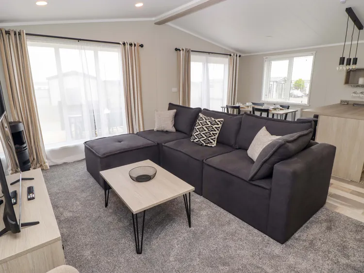 Bright open-plan sitting room with electric fire and Smart TV at Awel y Môr (Dolphin)