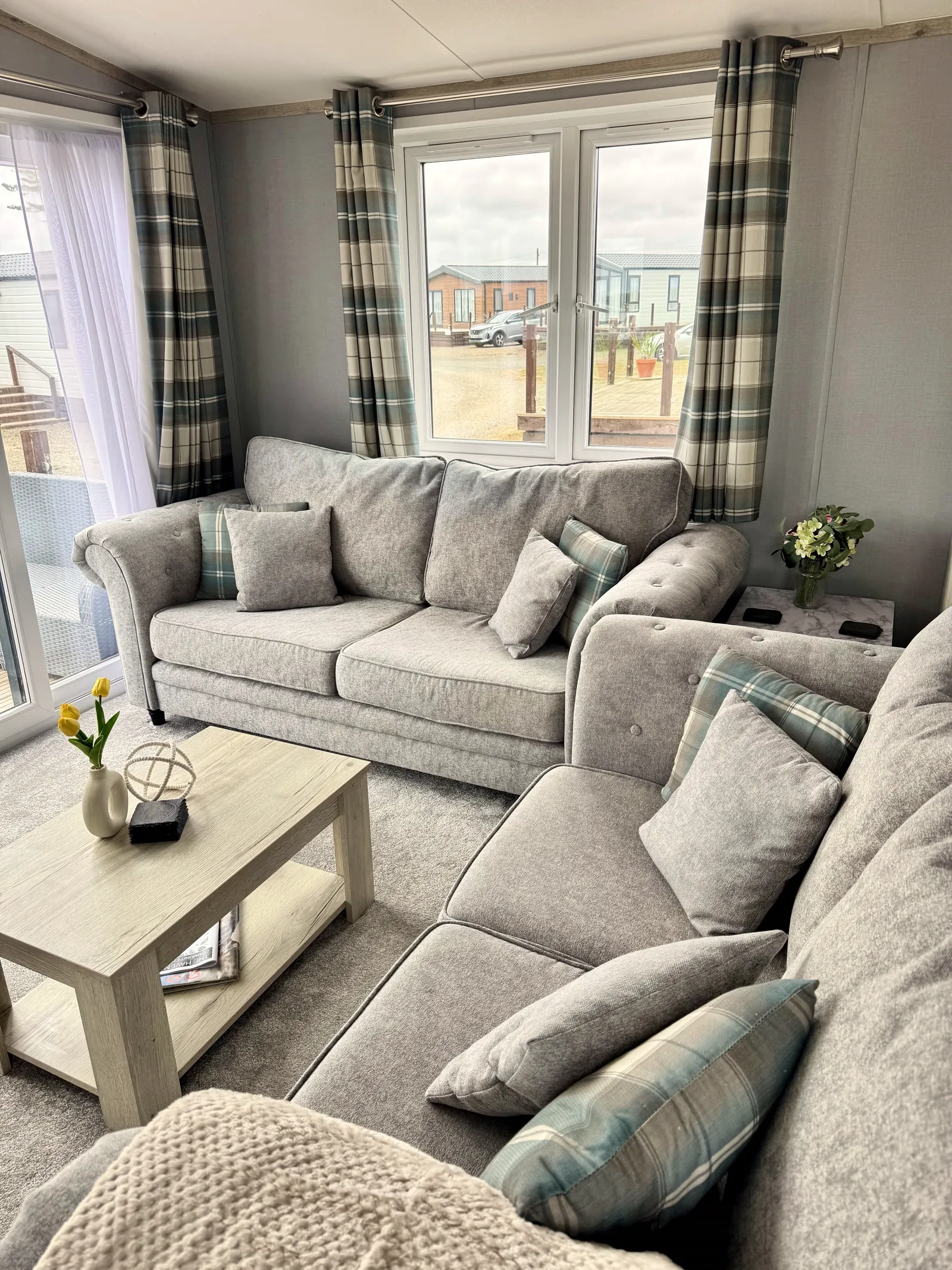 Open-plan lounge at Tŷ'r Môr with corner sofa, coffee table and large windows looking out across Little Haven Retreat
