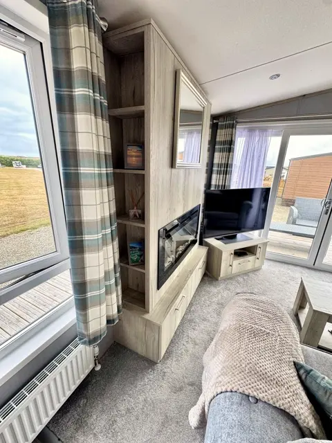 Sitting area at Tŷ'r Môr with electric fire, TV and patio doors onto the private decking