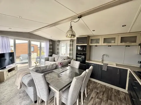 Dining table and chairs beside the kitchen at Tŷ'r Môr, with views out to the decking