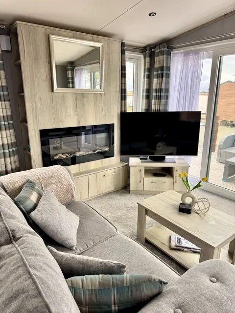 Lounge at Tŷ'r Môr with electric fire, Smart TV and soft grey seating