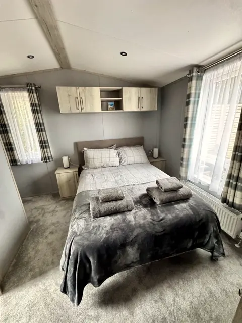 King-size bedroom at Tŷ'r Môr with made-up bed, fresh towels and soft carpet