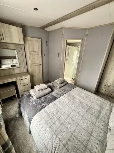 King-size bed at Tŷ'r Môr dressed with towels ready for arrival