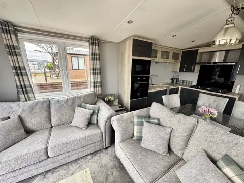 Living space at Tŷ'r Môr looking through to the kitchen, with corner sofa and pendant lighting