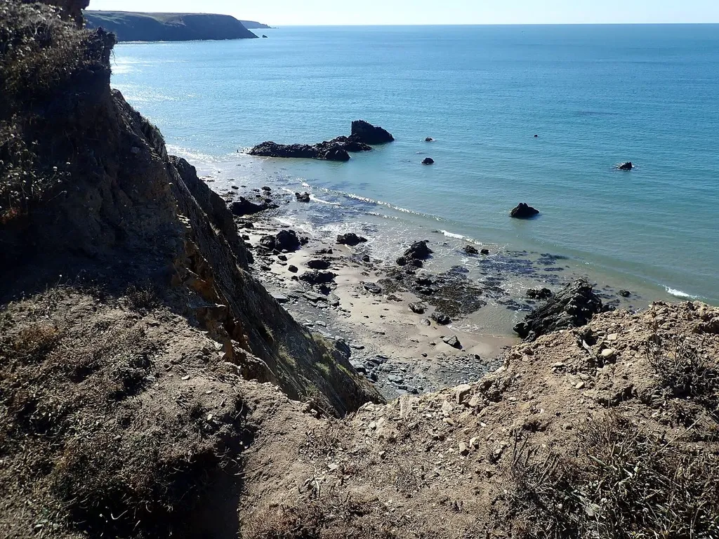 Marloes Sands beach with layered cliffs and the Three Chimneys rock formation