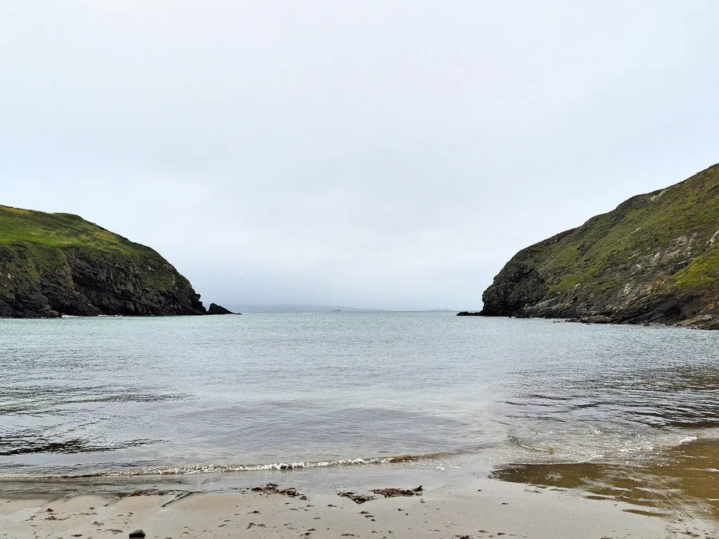 Quiet horseshoe cove at Nolton Haven between grassy headlands